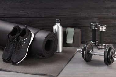 Gri ahşap masada birçok farklı spor ekipmanı var.