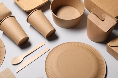 Çevre dostu gıda ambalajı. Açık gri arkaplanda kağıt kaplar ve sofra takımı