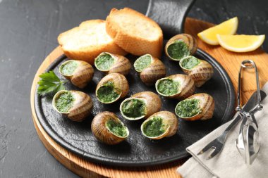 Gri desenli masada servis edilen lezzetli pişmiş salyangozlar.