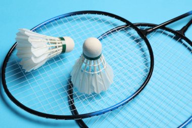 Tüy badminton mekik horozları ve raketler açık mavi arka planda, yakın plan