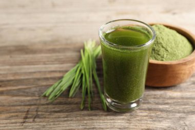 Buğday çimi, ahşap masadaki shot bardağında içer, yakın plan. Metin için boşluk