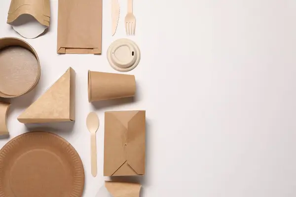 Eco friendly food packaging. Paper containers, bag and tableware on white background, flat lay. Space for text