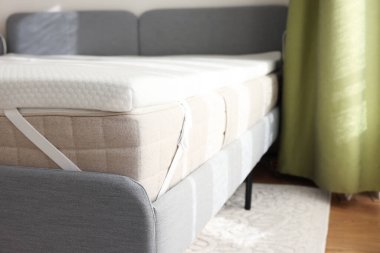 Beyaz hatıra köpüklü döşek üstü kapalı gri yatakta.