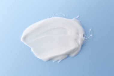 Açık mavi arka planda vücut bakım kremi örneği, üst görünüm