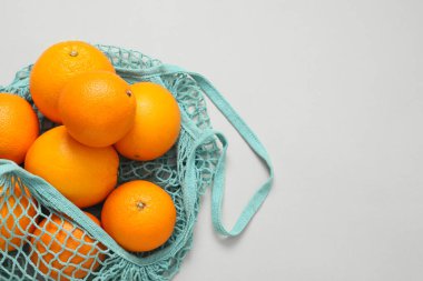 Açık arkaplanda taze portakallı ip torbası, üst manzara. Metin için boşluk