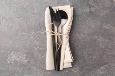 Gri desenli masa üzerinde şık çatal bıçak seti ve peçete.