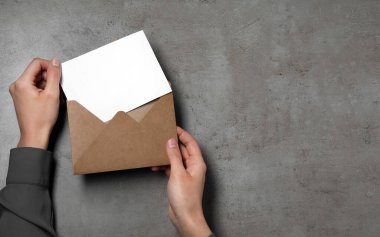 Gri desenli masadaki zarftan kart alan kadın. Metin için boşluk