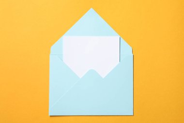 Turuncu arka planda, açık mektup zarfında boş bir sayfa, üst görünüm