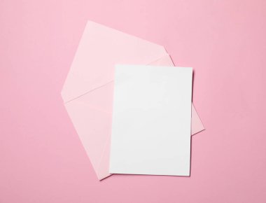 Zarf ve kart pembe arkaplanda, üst görünümde