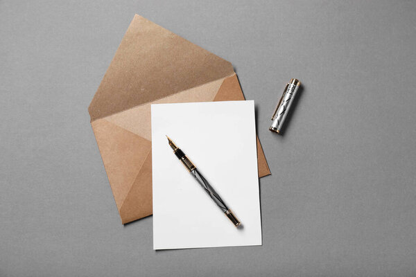 Blank sheet of paper, letter envelope and pen on grey background, top view