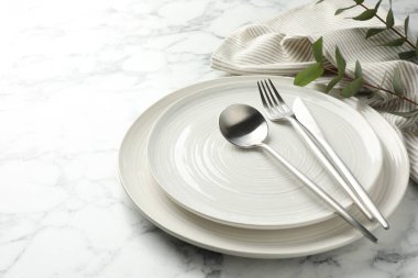 Çatal bıçak takımı, peçete, okaliptüs dalları ve beyaz mermer masa üzerindeki tabaklar, yakın plan. Metin için boşluk