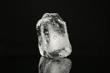 Siyah ayna yüzeyinde berrak buz parçası