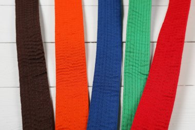 Ahşap arka planda renkli karate kemerleri, düz yatış