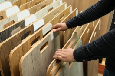 Dükkandaki farklı numuneler arasında ahşap döşemeyi seçen adam, yakın plan.