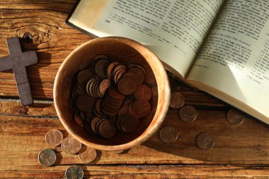 Bağış yap ve konsept ver. Bozuk paralarla, haçla ve İncil 'le ahşap masada, düz yatıyordu.