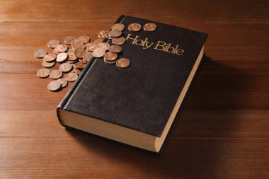 Bağış yap ve konsept ver. Tahta masanın üzerinde madeni paralar ve incil