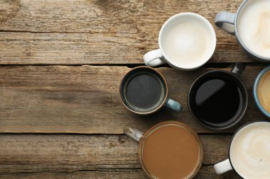 Tahta masadaki fincanlarda farklı kahve içecekleri, düz yatış. Metin için boşluk