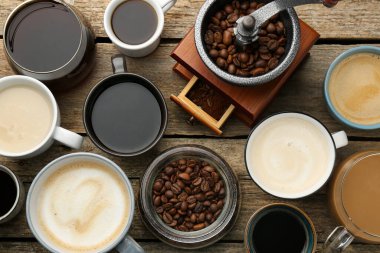 Farklı kahve fincanlarında, fasulyelerde ve ahşap masada el değirmeninde, düz yerde.