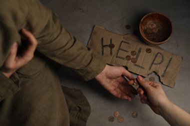 Evsizlere para veren bir kadın, yakın plan. Çimentoya bağışta bulunarak imzala ve yuvarla.
