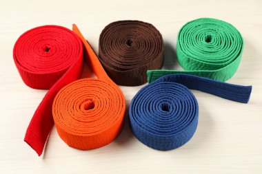 Ahşap arka planda renkli karate kemerleri. Dövüş sanatları üniforması