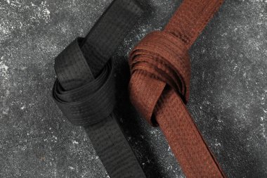 Gri dokulu arka planda siyah ve kahverengi karate kemerleri, düz yatıyordu