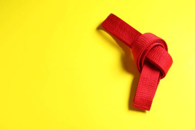 Sarı arka planda kırmızı karate kuşağı, üst manzara. Metin için boşluk