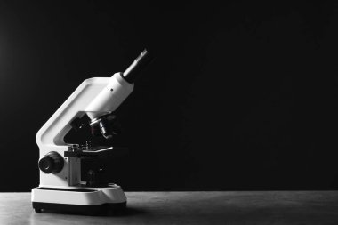 Siyah arkaplana karşı gri tabloda modern mikroskop, metin için boşluk