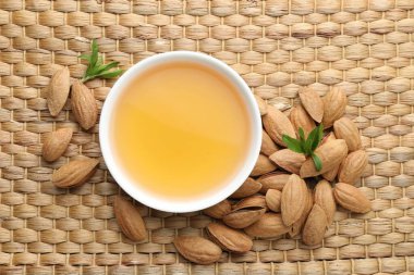 Kavanozda badem yağı, fındık ve yapraklar hasır masada, düz yatıyordu