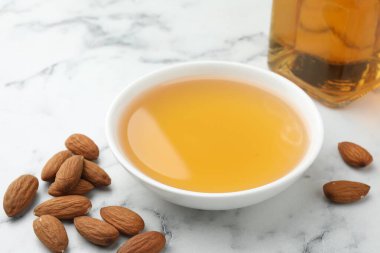 Kavanozda badem yağı, beyaz mermer masada fındık, yakın plan.