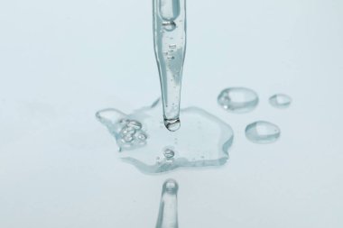 Işık arka planında cam pipet ve şeffaf sıvı, yakın plan