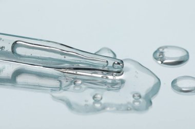 Işık arka planında cam pipet ve şeffaf sıvı, yakın plan
