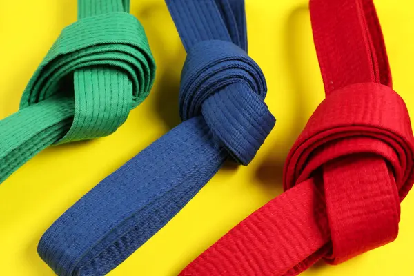 Sarı arkaplanda renkli karate kemerleri, yakın plan