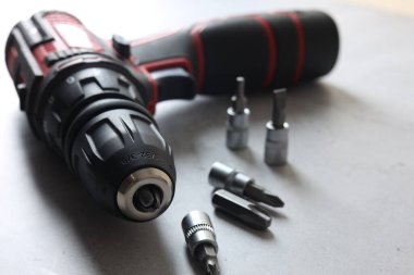 Modern elektrikli tornavida ve gri masadaki parçalar, yakın plan.