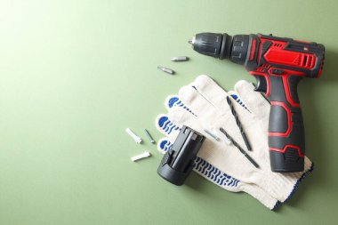 Elektrikli tornavida, soluk yeşil arka planda eldivenler ve aksesuarlar.