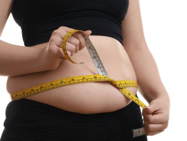 Beyaz arka planda bantlı bir kadın göbeğini ölçüyor, yakın plan. Aşırı kilolu