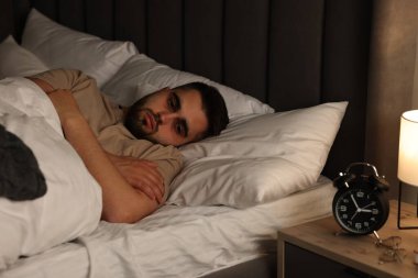 Yatakta uykusuzluk çeken sinirli bir adam.