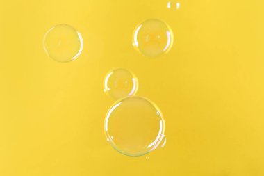 Sarı arka planda güzel şeffaf sabun köpükleri