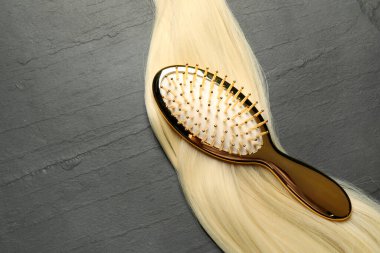 Koyu gri masada sarı saç telli şık fırça, üst manzara. Metin için boşluk