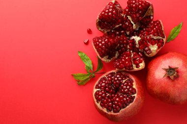 Taze nar ve yeşil yapraklar kırmızı arka planda, düz yerde. Metin için boşluk