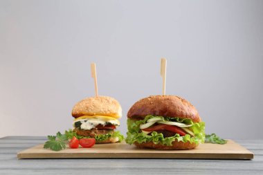 Gri ahşap masada servis edilen lezzetli vejetaryen hamburgerler.