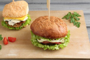 Gri ahşap masada servis edilen lezzetli vejetaryen hamburgerler.