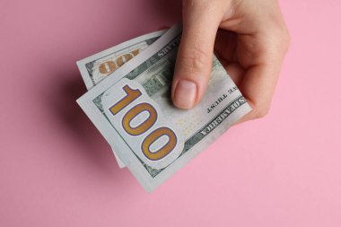 Para değişimi. Pembe arka planda dolar banknotları tutan kadın.