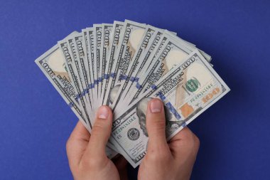 Para değişimi. Mavi arka planda dolar banknotları tutan adam, üst görünüm