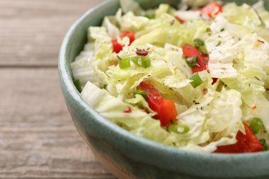 Çin lahanalı lezzetli salata, dolmalık biber ve ahşap masada yeşil soğan, yakın plan.