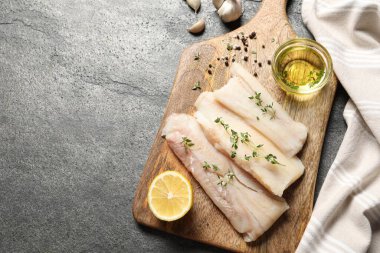 Çiğ morina balığı, mikroyeşiller, yağ, baharatlar ve limon gri dokulu masa, üst manzara. Metin için boşluk