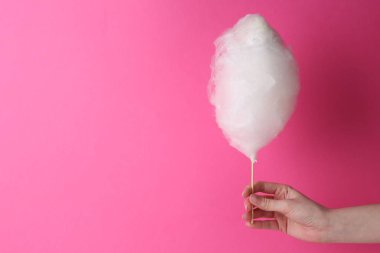 Pembe arka planda elinde pamuk şeker tutan bir kadın, yakın plan. Metin için boşluk