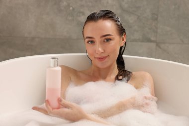 Banyoda duş jeliyle banyo yapan bir kadın.