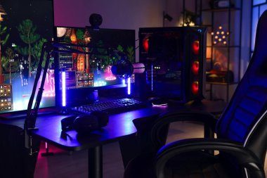 Video oyunları oynuyorum. Modern bilgisayar ve neon lambalı oyun koltuğu olan şık bir oda.