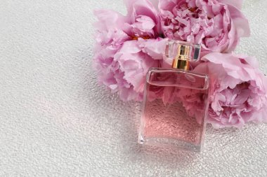 Beyaz plastik yüzeyde lüks parfüm ve çiçek dekoru, metin için boşluk