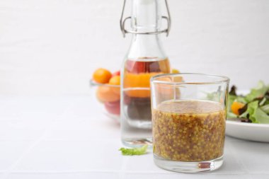Açık fayanslı masa üzerinde cam içinde lezzetli sirke tabanlı sos (Vinaigrette), yakın plan. Metin için boşluk